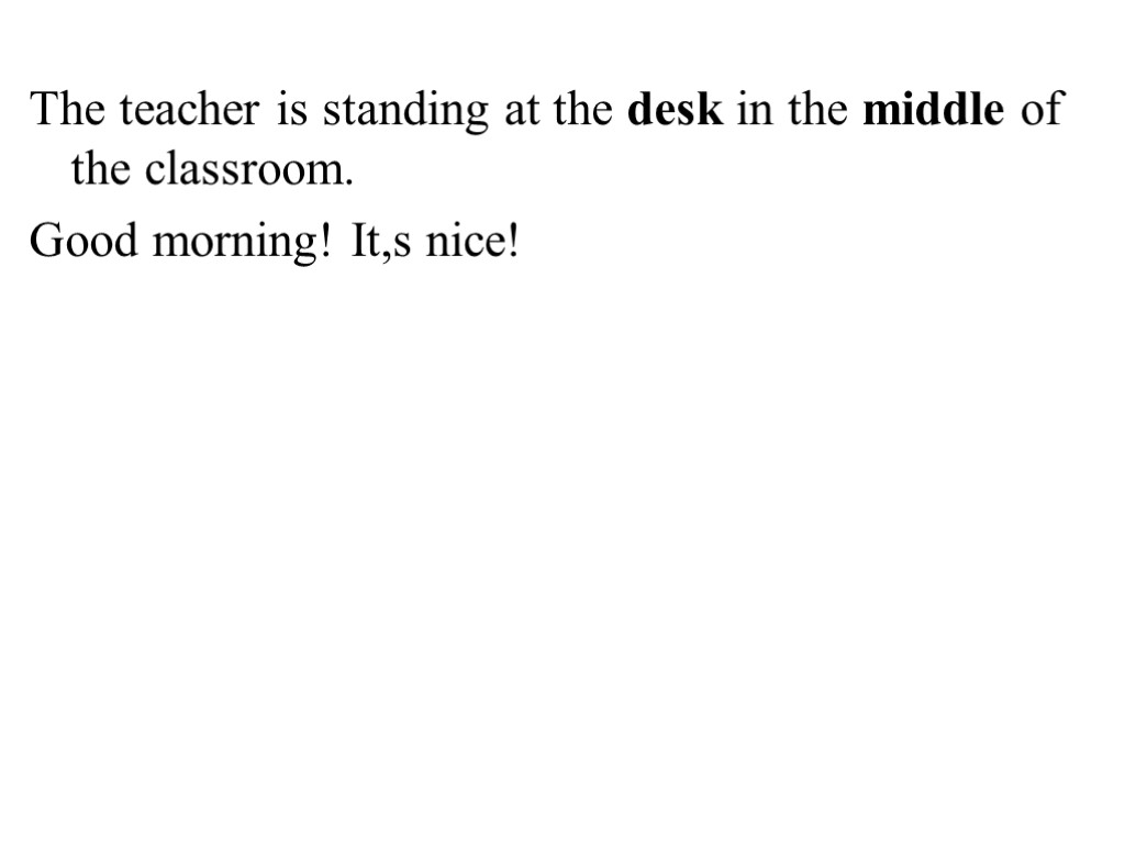 The teacher is standing at the desk in the middle of the classroom. Good